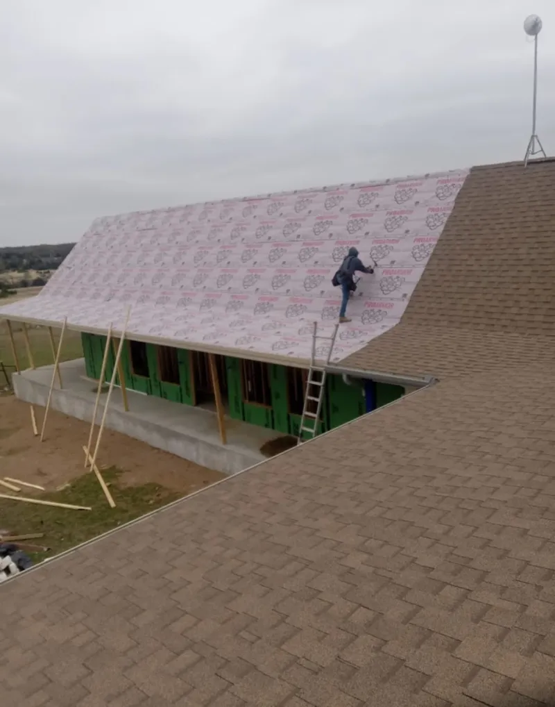 Worker preparing underlayment for a metal roof installation in Longswamp
